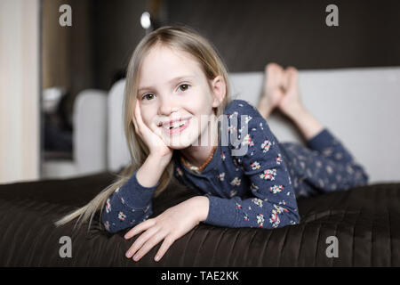 Retrato de niña sonriente con el hueco del diente relajándose en sofá en casa