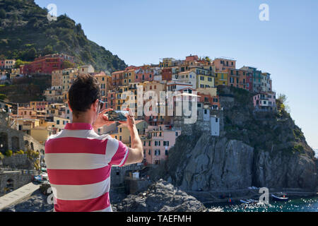 Italia, Liguria, La Spezia, el Parque Nacional de Cinque Terre, hombre usando smartphone, fotografiando Manarola Foto de stock