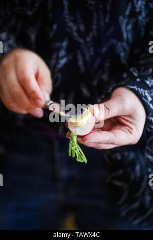 Mujer extendiendo la mantequilla en un rábano fresca cruda Foto de stock