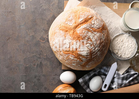 Sabroso pan con los ingredientes de la masa, sobre fondo gris