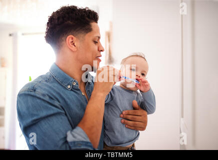 Padre e hijo en un niño pequeño baño interiores en casa, cepillado de los dientes. Foto de stock