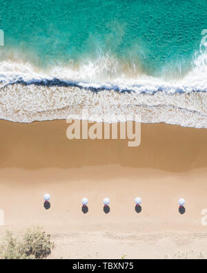 Vista aérea de sombrillas de playa, olas azules del océano y relajantes vibraciones en la costa oriental de Australia