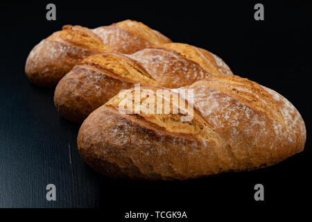 Sabrosos panes recién horneados sobre una mesa oscura. Deliciosos productos horneados directamente de la panadería. Fondo negro.