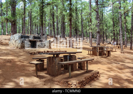 Mesas de madera y piedra para picnic y parrillas para barbacoa bosque de pino canario, Esperanza, Tenerife. Foto de stock