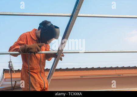 Soldadura por trabajador en Orange la ropa de trabajo de soldadura para  armazón de techo Fotografía de stock - Alamy