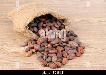 Cacao en grano en bolsa sobre fondo de madera Foto de stock