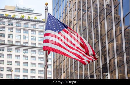 Símbolo de EE.UU. en las calles de Nueva York. La bandera americana en el centro de Manhattan, edificios altos de negocios antecedentes Foto de stock