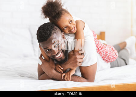 Hombre afroamericano abrazando con su pequeña hija