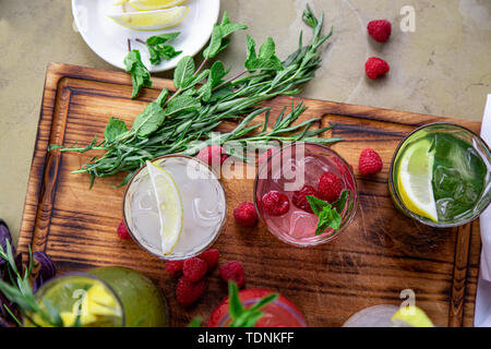 Los refrescos de verano, un conjunto de las limonadas. Las limonadas en jarras sobre la mesa, los ingredientes que los componen están dispuestas alrededor.