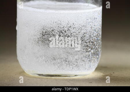 Primer plano de un vinagre y bicarbonato de sodio reacción ocurre en el fondo de un tarro de vidrio; reacciones violentas con muchas burbujas Foto de stock