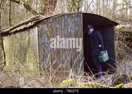 Youn mummed hombre con gas puede entrar en el garaje de hierro corrugado sórdido vacío, en Alemania, en Renania del Norte-Westfalia Foto de stock