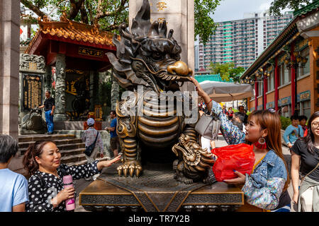 Los turistas chinos rozar la estatua del Dragón para atraer la buena suerte a la entrada de Wong Tai Sin Temple, Hong Kong, China Foto de stock