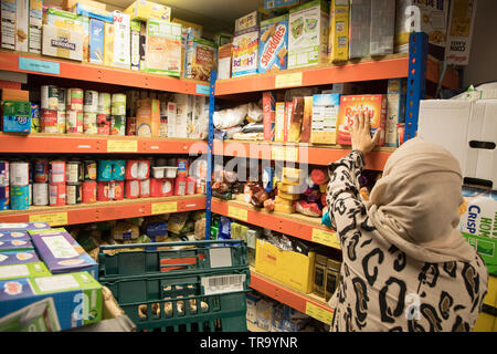 Una mujer musulmana con un velo bolsas de embalaje en un banco Foto de stock