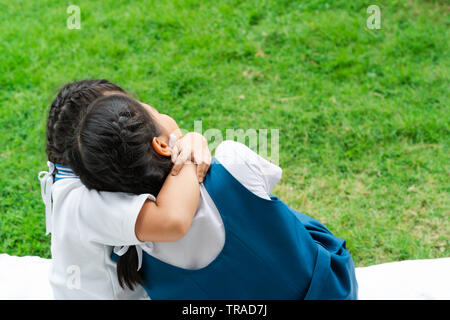 Dos pequeños Asian Girls hermanas abrazos feliz post en uniforme escolar, concepto de vuelta a la escuela Foto de stock
