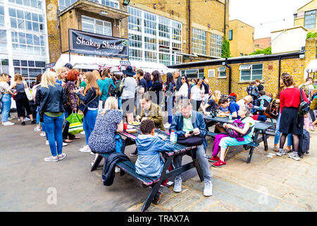 El 27 de mayo de 2019 personas sentadas en el patio de la casa de caldera libre de comer en el Festival, London, UK Foto de stock