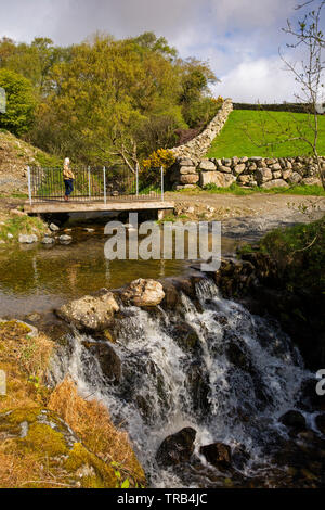Irlanda del Norte, Co abajo, Baja, mujer Crockbane Mournes, cruzando el puente del pie en agua Cassy Ford Foto de stock