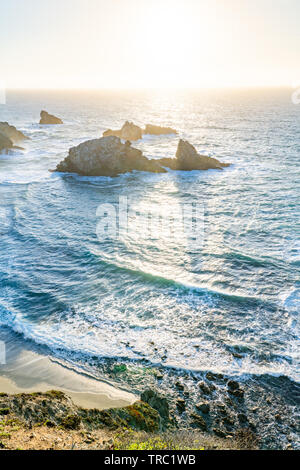 La puesta del sol crea sombras detrás de pilas de mar a lo largo de una hermosa costa, Big Sur, California, Estados Unidos.