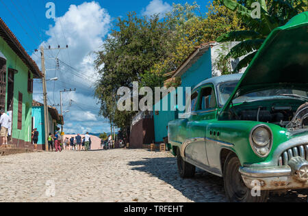 Clásico americano coche verde en espera de reparación en una de las calles empedradas de la antigua ciudad colonial de Trinidad, Sancti Spíritus, Cuba, El Caribe
