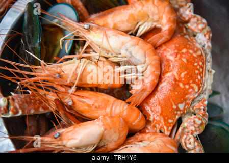 El plato de pescado con mariscos camarones al vapor gambas mejillones hervidos en la olla caliente con hierbas y especias en fondo Foto de stock