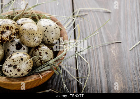Huevos de codorniz orgánicos frescos en recipiente de madera de estilo rústico en la mesa de la cocina. Espacio para el texto