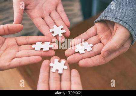 Closeup imagen de muchas personas manos sosteniendo y colocando un pedazo de rompecabezas blanco juntos