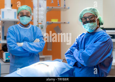 Equipo de cirujanos en crecido uniforme máscara y brazo transversal en el quirófano. El equipo prepara para cirugía en Fotografía de stock