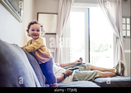 Niña feliz con el padre en el sofá en casa