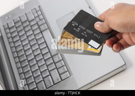 Persona&#39;s mano sujetando las tarjetas de crédito a través de un portátil