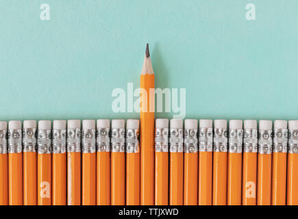 Fila de lápices de color naranja con un lápiz afilado. Liderazgo / pie de una muchedumbre concepto con espacio de copia.