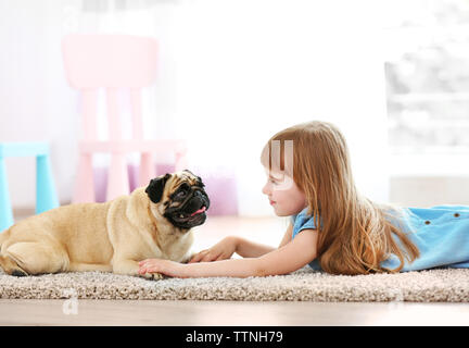 Linda niña jugando con el perro en alfombras