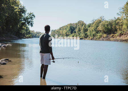 Vista lateral del hombre que pesca con la barra en el lago
