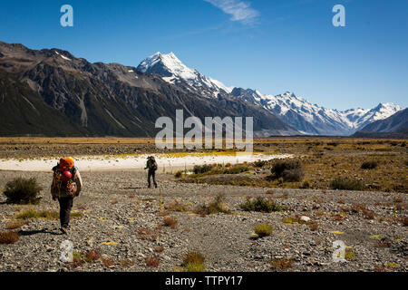 Figura caminando hacia distantes montañas cubiertas de nieve en Nueva Zelanda Foto de stock
