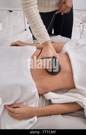 Sección media de la doctora utilizando equipos médicos al tratar el paciente en clínica médica Foto de stock