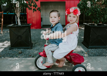 Retrato de los hermanos lindo caballo bicicleta sobre la acera en el patio Foto de stock