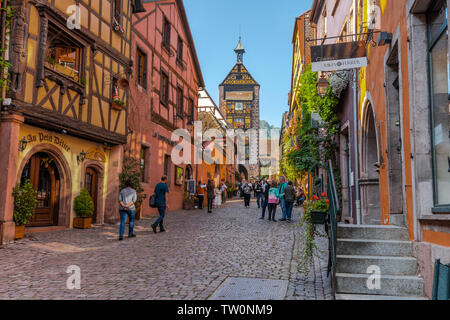 Calle del casco antiguo de Riquewihr, Alsacia, Francia, marco típico y la muralla de la ciudad con la torre Foto de stock