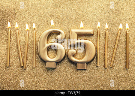 Número 65 celebración de oro sobre un fondo brillante velas Foto de stock