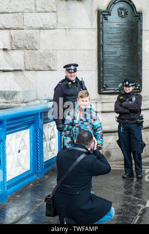 Un padre que toma una fotografía a su joven hijo y dos funcionarios de la Policía Metropolitana de Londres. Foto de stock