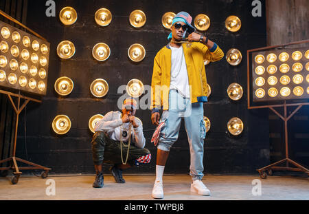 Los raperos en caps bailar en el escenario con proyectores Foto de stock