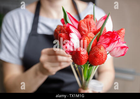 Mujer hace un original Ramo de tulipanes hermosos y las fresas maduras Foto de stock