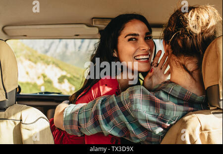 Mujer sonriente abrazando a su novio la conducción de un coche. Pareja amorosa en un coche en vacaciones.