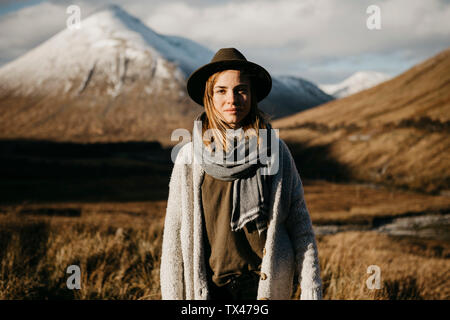 Reino Unido, Escocia, Loch Lomond y los Trossachs National Park, retrato de mujer joven con sombrero en el paisaje rural