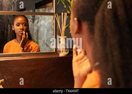 Mujer joven mirando en el espejo del baño