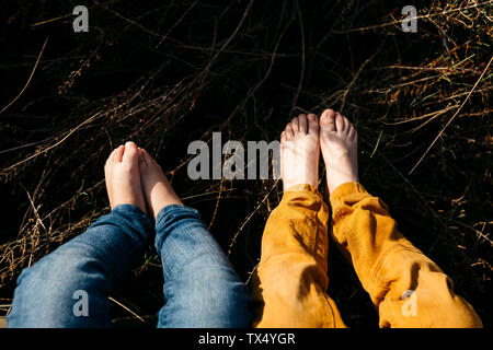 Los pies de la niña y su hermano mayor en la naturaleza, close-up