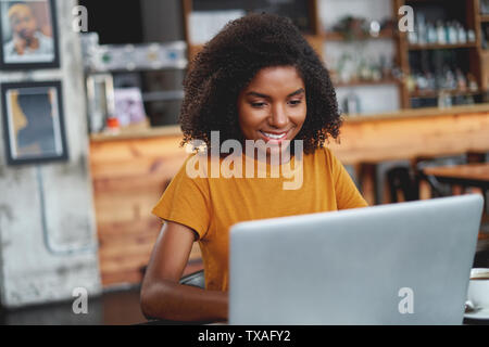 Mujer joven con laptop en cafe