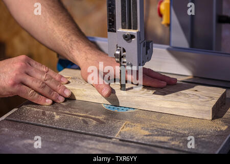 Detalle de la mano de un carpintero junto a una banda de la hoja de la sierra. El concepto de la seguridad en el trabajo y accidentes. Foto de stock