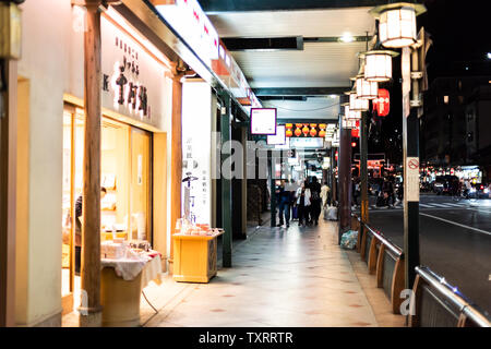 Kyoto, Japón - Abril 16, 2019: la famosa calle de tiendas en el distrito Gion de noche iluminado con luces y la gente caminando en la acera por las tiendas Foto de stock