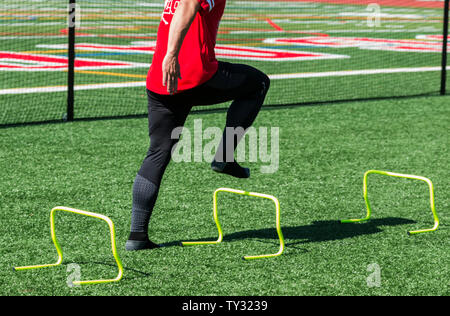 Una escuela secundaria es atleta de pista y campo, superando yellow mini vallas sin zapatos para ayudar a desarrollar la fuerza del pie.