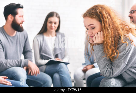 Malestar pelirroja mujer sentada a sesiones de terapia de grupo Foto de stock