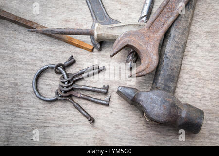 Manojo de llaves diferentes y herramientas de mano en placa de madera, mantenimiento y reparing concepto