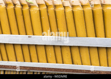 Pilas de amarillo vidriado de cerámica azulejos de techo curvo en un patrón simétrico. Foto de stock